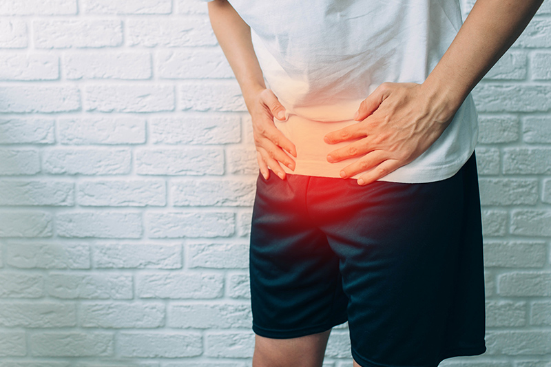 下腹部に違和感を感じ腰に手を当てる男性
